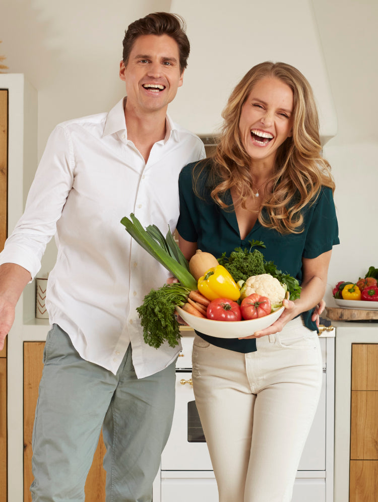 Kristel and Michael laughing while holding a large plate of vegetables